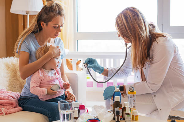 Pediatric doctor in a fellowship program tending to a young toddler with the flu